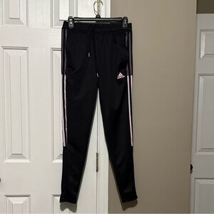 Women’s Black Adidas Tiro track pants with pink stripes.